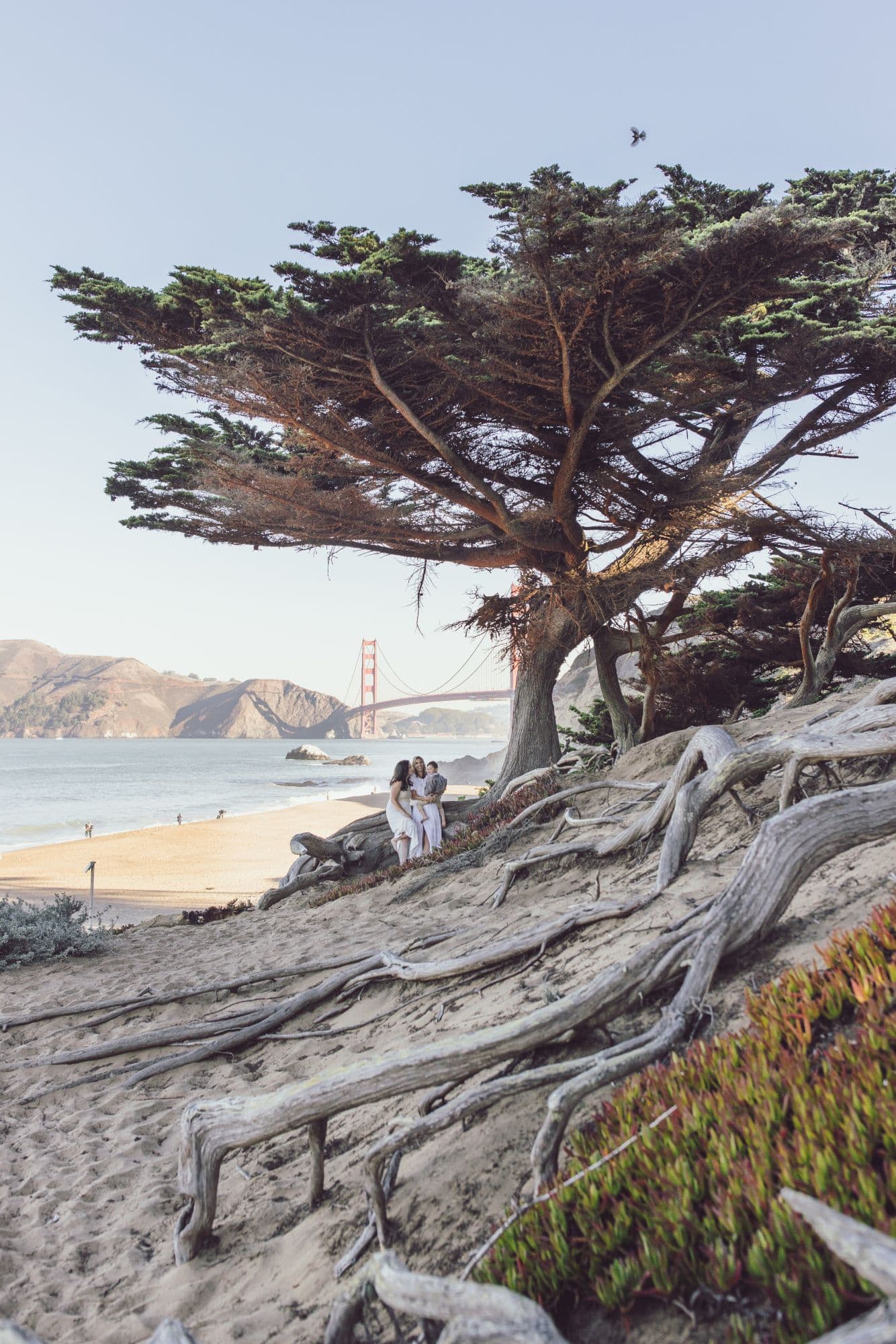 Family photo session at Baker Beach with a clear view of the Golden Gate Bridge in San Francisco